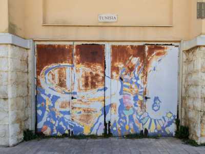 Anche la porta successiva, dedicata alla Tunisia, non � pi� quella di una volta: nella parte superiore la ruggine impedisce infatti di riconoscere la rappresentazione originaria